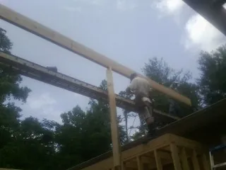 Carpenter setting a ridge beam over a new addition frame — Ice Dam Removal by Roofing Brothers in Pine Bluff