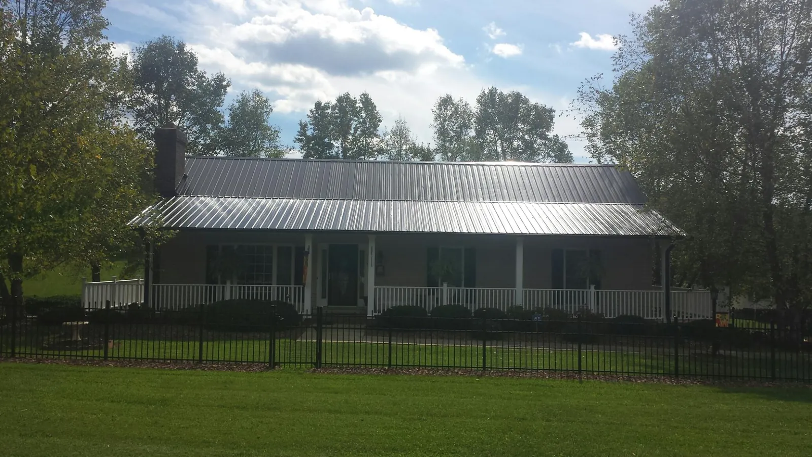 Gray metal roof on a brick ranch with a full width front porch — Gutter Guard Installation work by our crew in Pine Bluff
